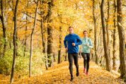 Junges Pärchen joggt im goldenen Herbstwald Junges Pärchen joggt im goldenen Herbstwald
